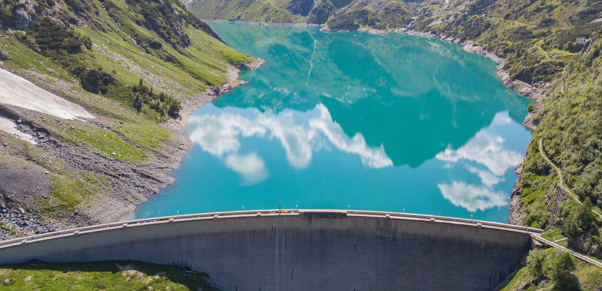 A dam forms an artificial lake in the mountains.