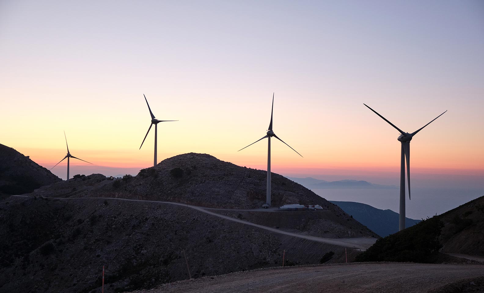 Series of wind turbines in the mountains at sunset
