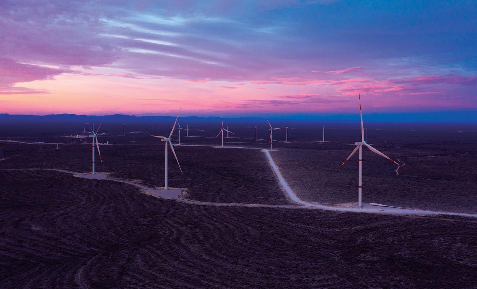 Panoramica su campo eolico al tramonto